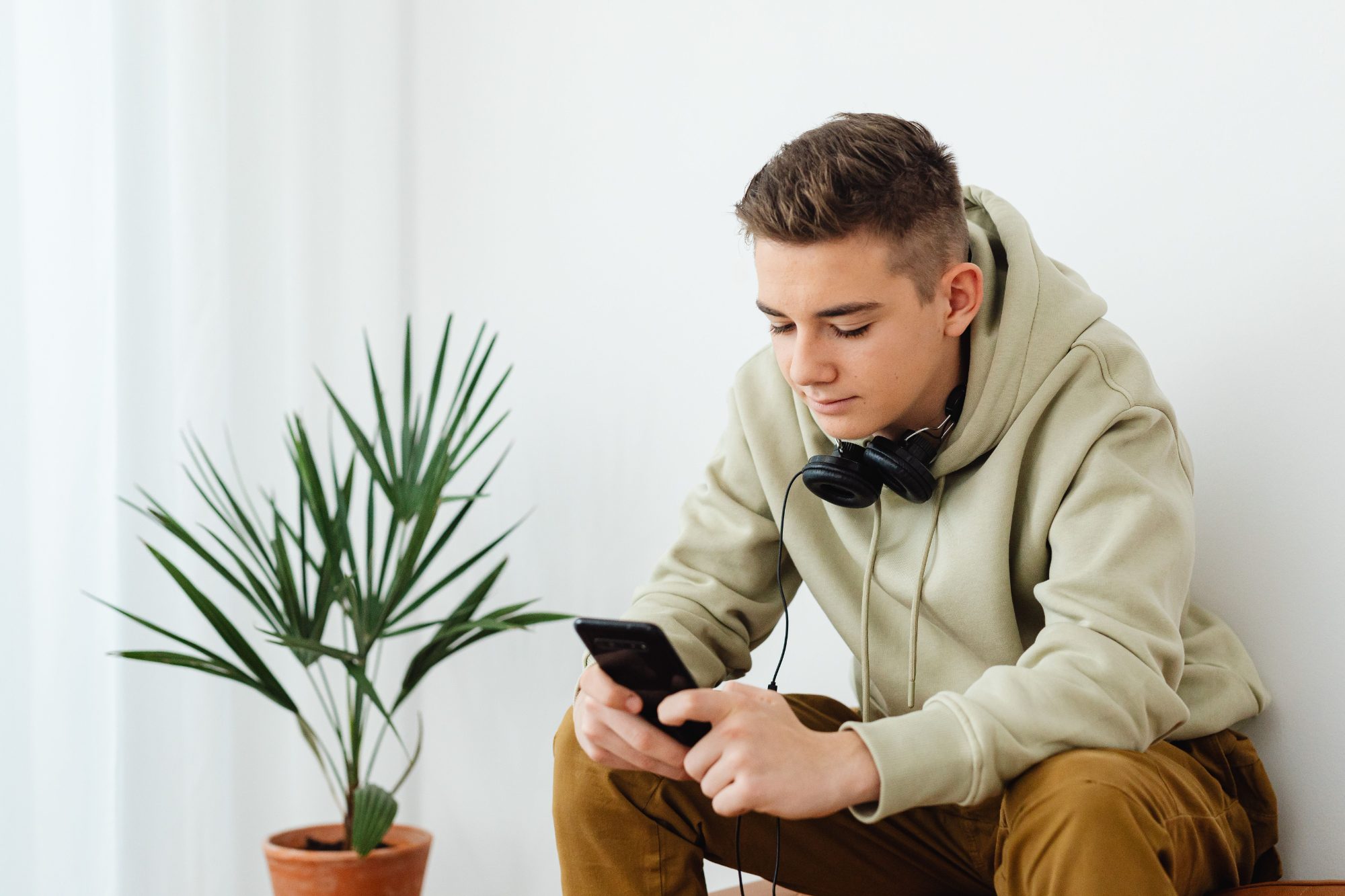 Junger Mann mit Kopfhörern schaut auf sein Handy