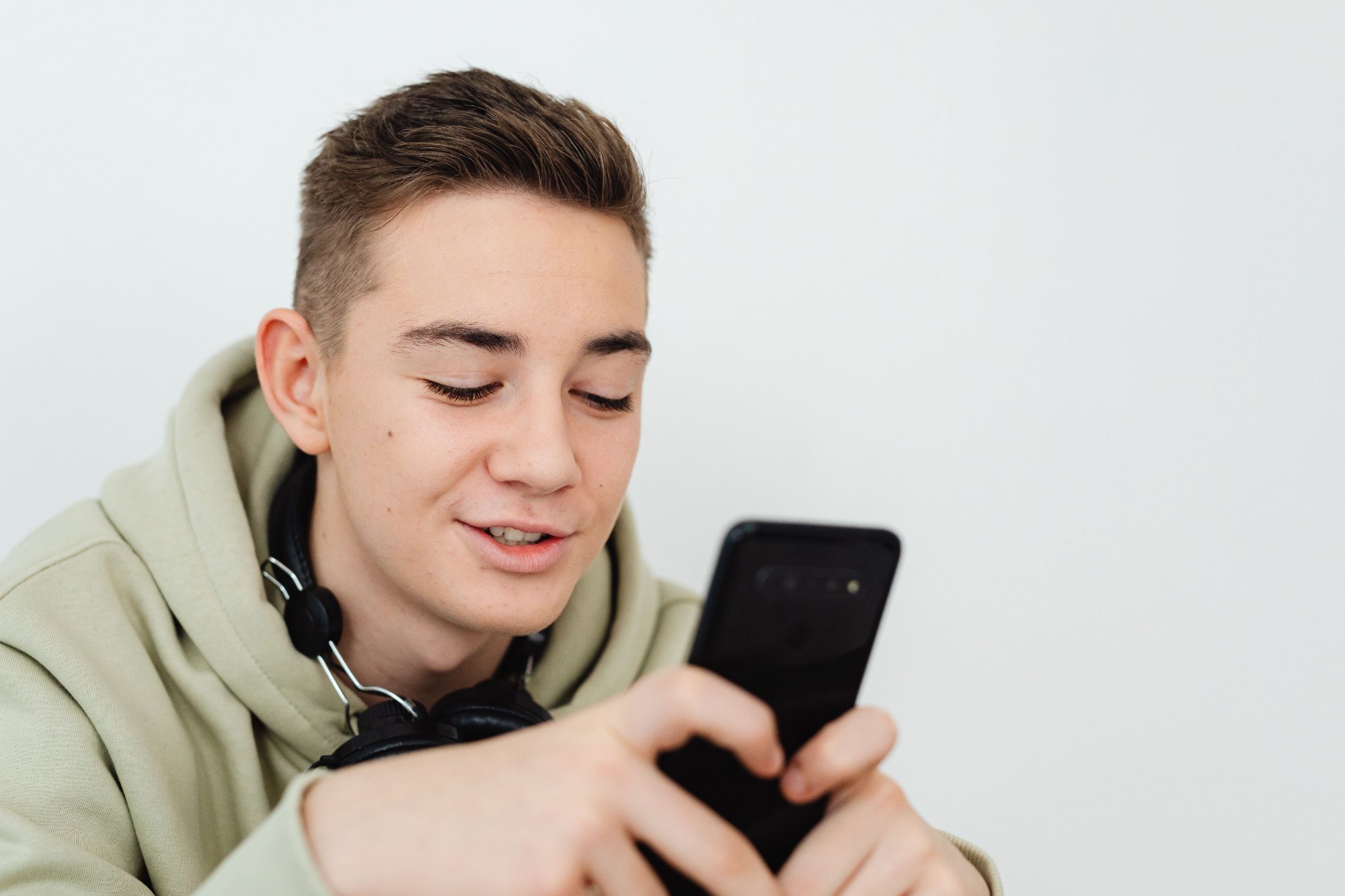 Junger Mann lächelt beim Schreiben auf dem Handy